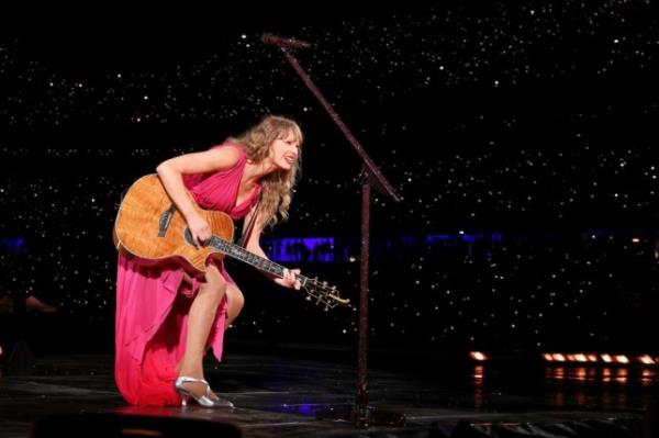 Taylor Swift holding a guitar on stage